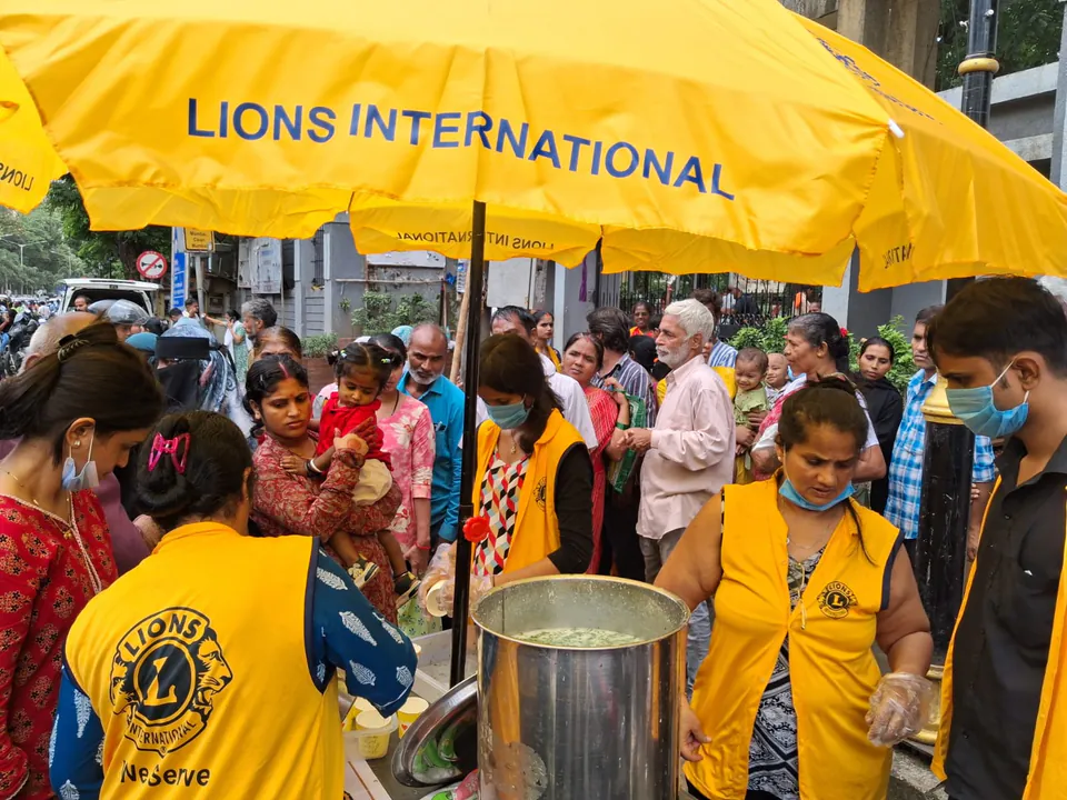 Lions Club volunteers in yellow jackets serving food in the community